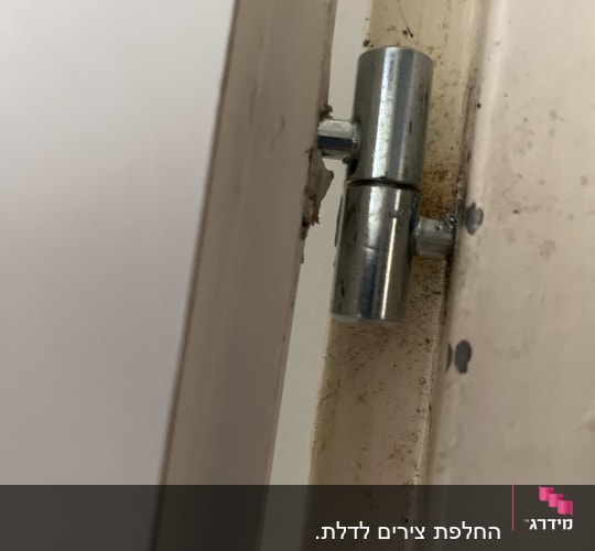 תקריב של ציר מתכת מותקן בדלת פנים ומשקוף